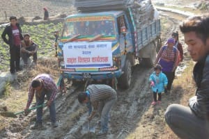 Local villagers removing obstacle of dirt for trucks to carry on further